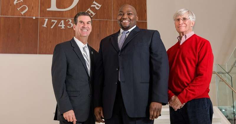 Three men in professional attire smiling at the camera