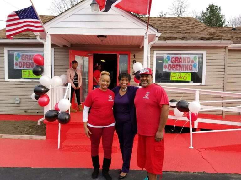 Three people standing in front of a restaurant at the grand opening