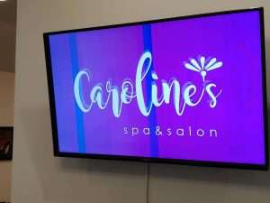 A tv displaying Caroline's Spa and Salon logo