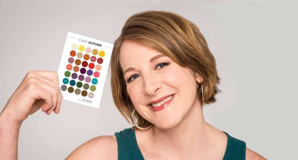 A smiling lady holding a multicolored makeup palette to her face