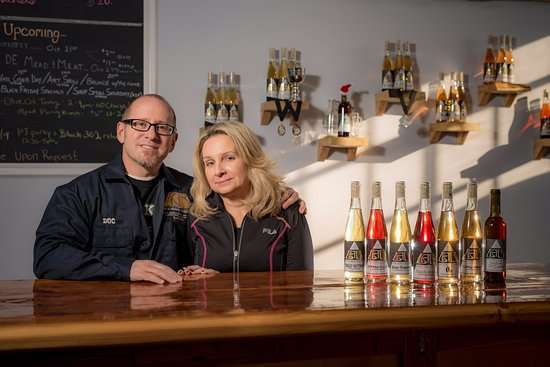 Two people sitting behind a table with bottles of liquid alchemy beverages