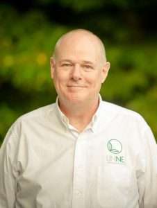 A headshot of a man in a white shirt