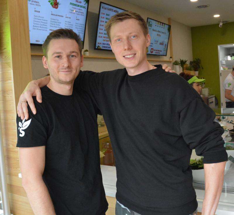 Two men in black shirts standing in a restaurant