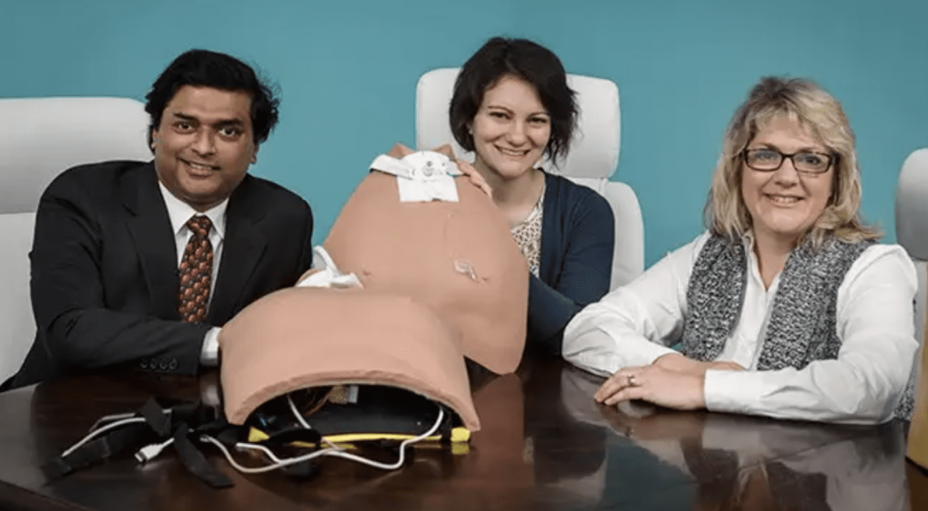 Three people sitting in a conference room with medical mannequin