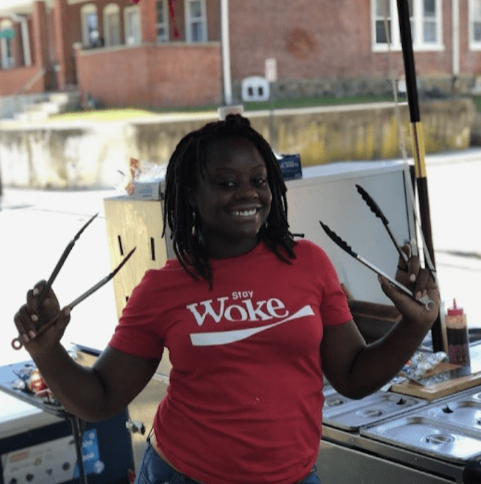 A lady in a red shirt holding cooking tongs in both hands