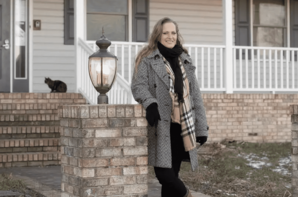 A woman in warm clothes standing in front of an inn