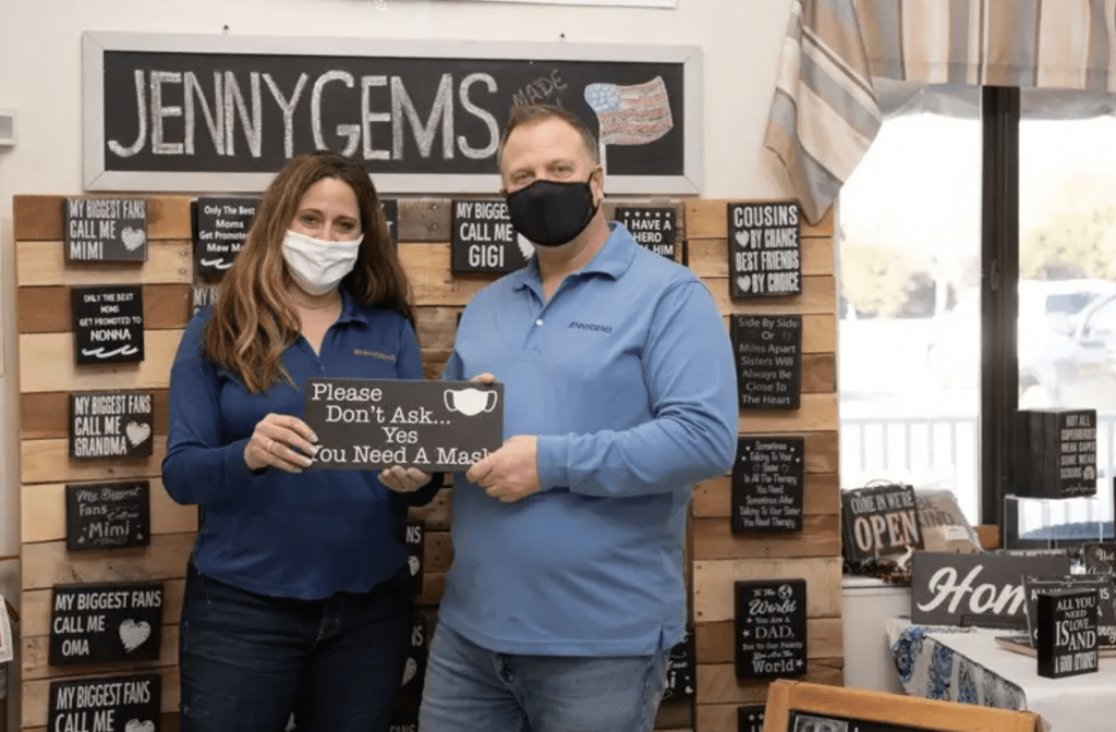 Two people standing in a shop wearing face masks.
