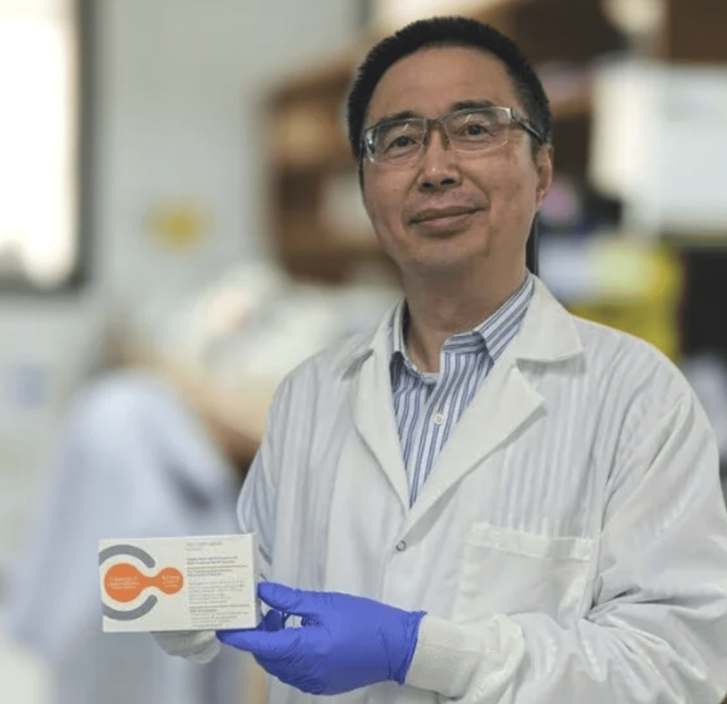 A man in a lab coat holding a pack of medicine