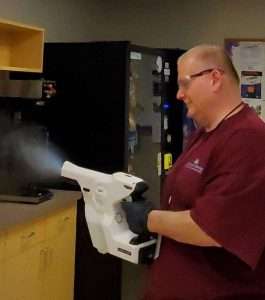 A man in a red shirt holding a white cleaning equipment
