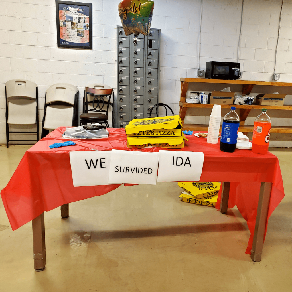 A red table with supplies on it with a note saying We Survived Ida.