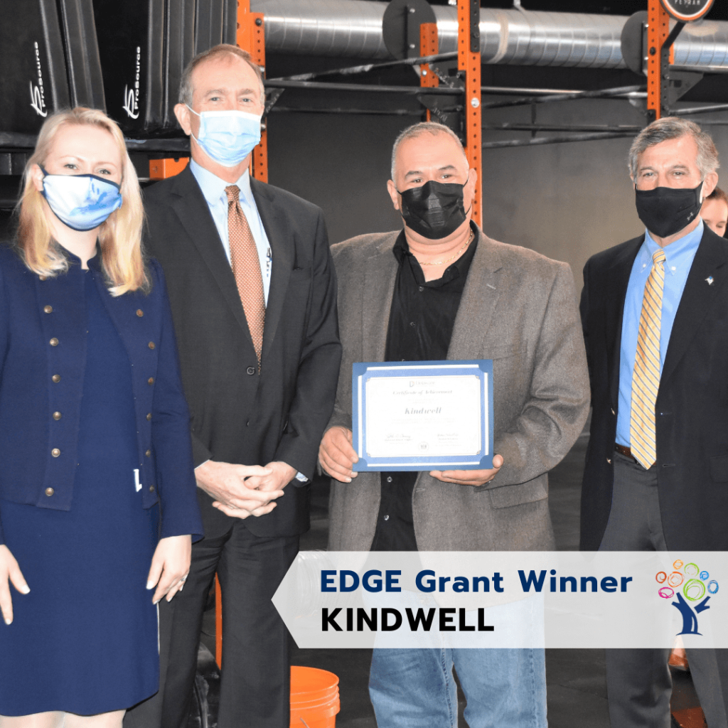 A group of three men and a lady holding an award at the EDGE Grant event.