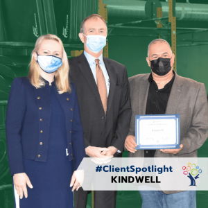 Three people in professional attire and nose masks displaying an award