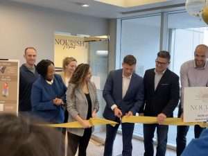 A group of people cutting the ribbon at the grand opening of Nourish Markets
