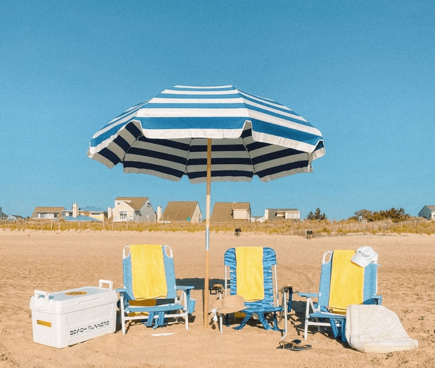 A setup at the beach with an umbrella and beach chairs