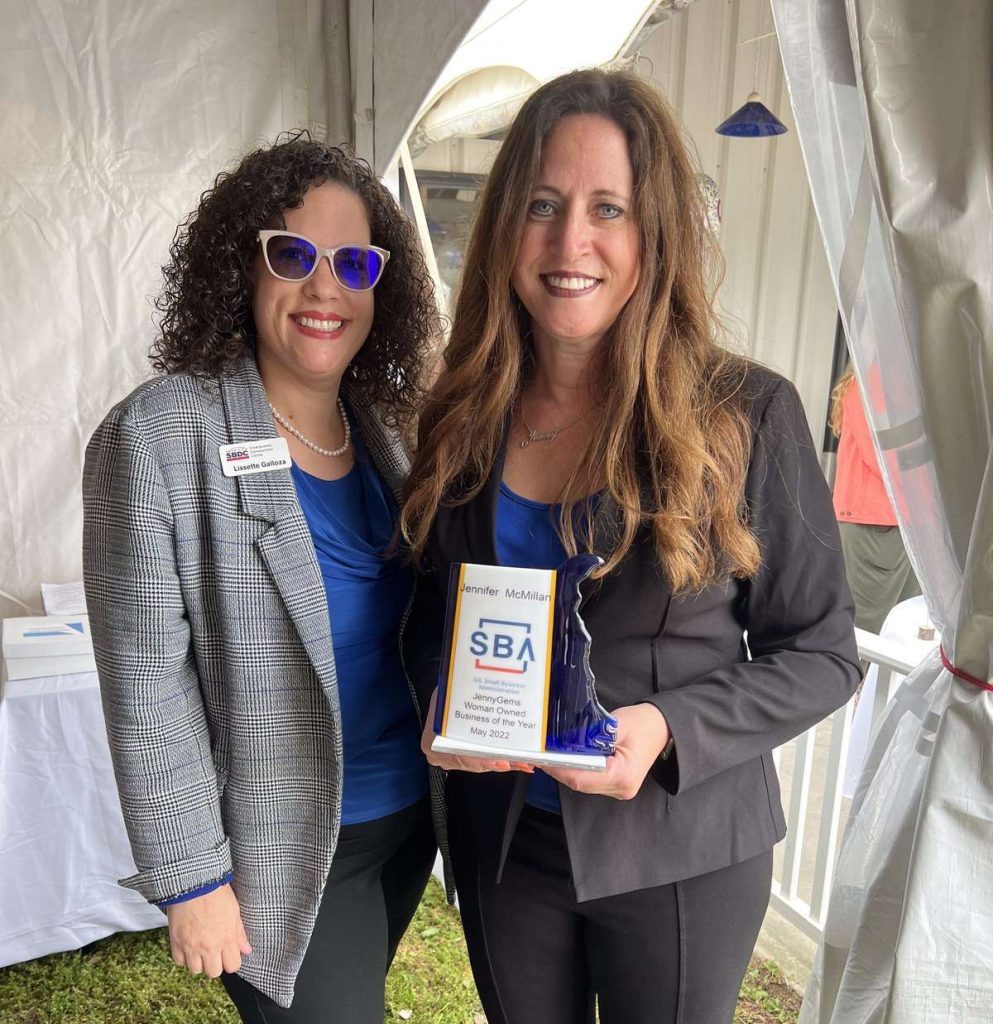 Two women in professional attire holding an award