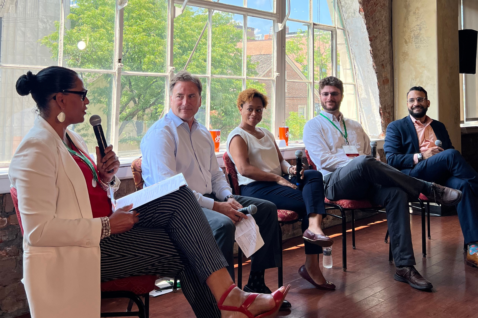 Delaware business advisor speaking at a panel discussion with three professionals listening attentively.