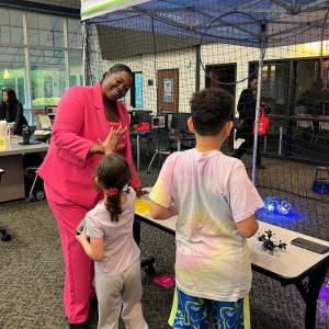 A black woman in a pink suit playing with kids.