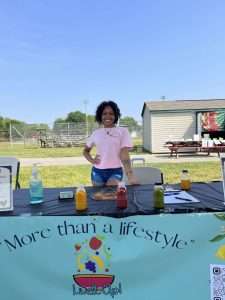 A young black woman standing at a fruit juice stand.
