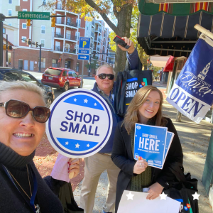 Three people holding fliers at Small Business Week