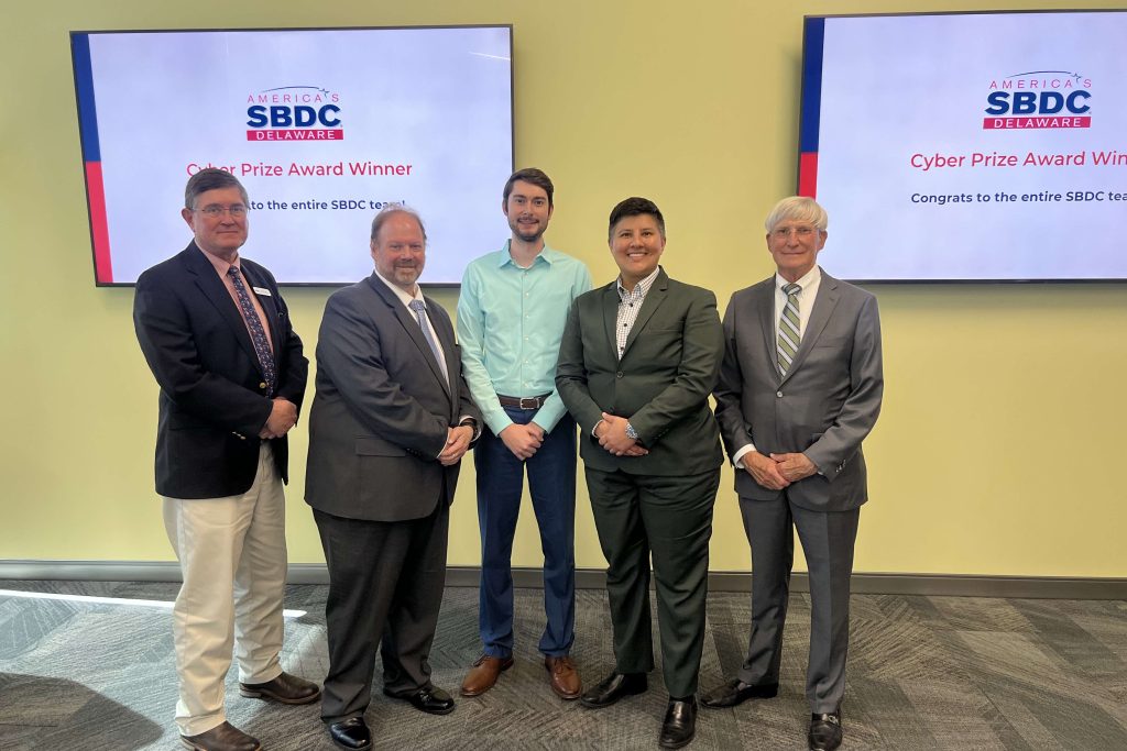 Delaware business advisor with a group of people standing in front of a TV