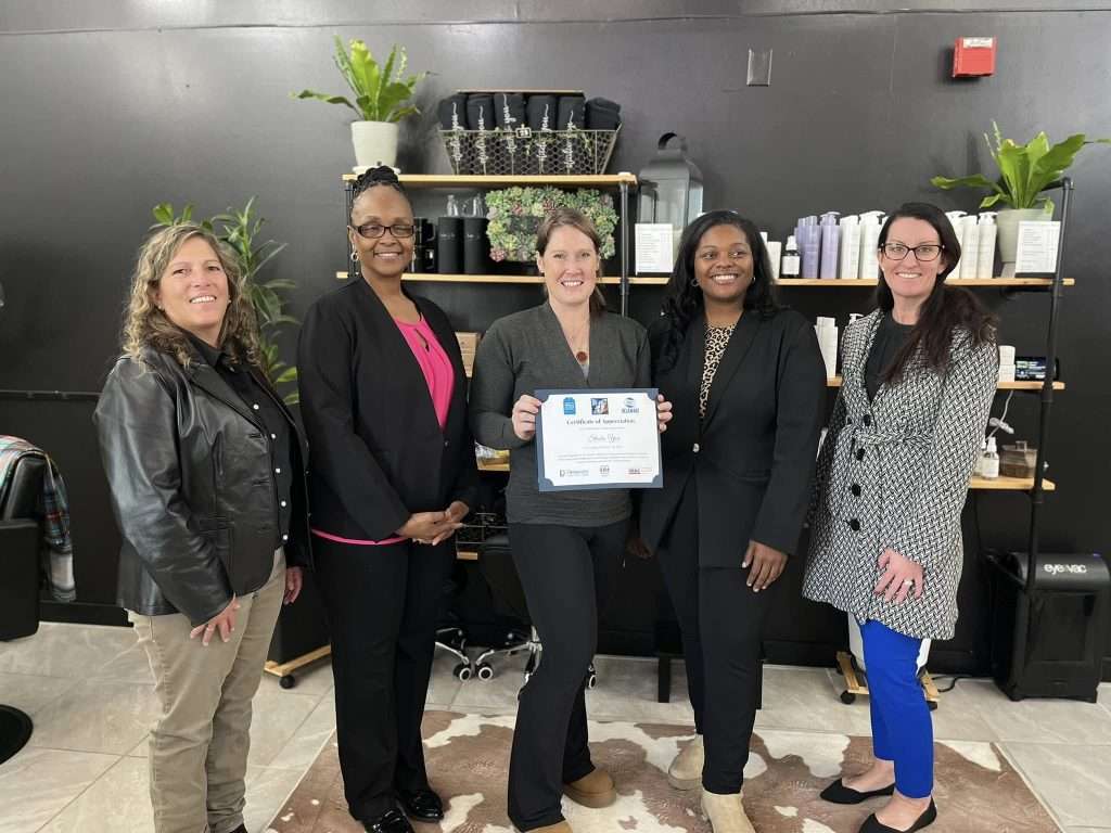 Five women in professional attired displaying a certificate