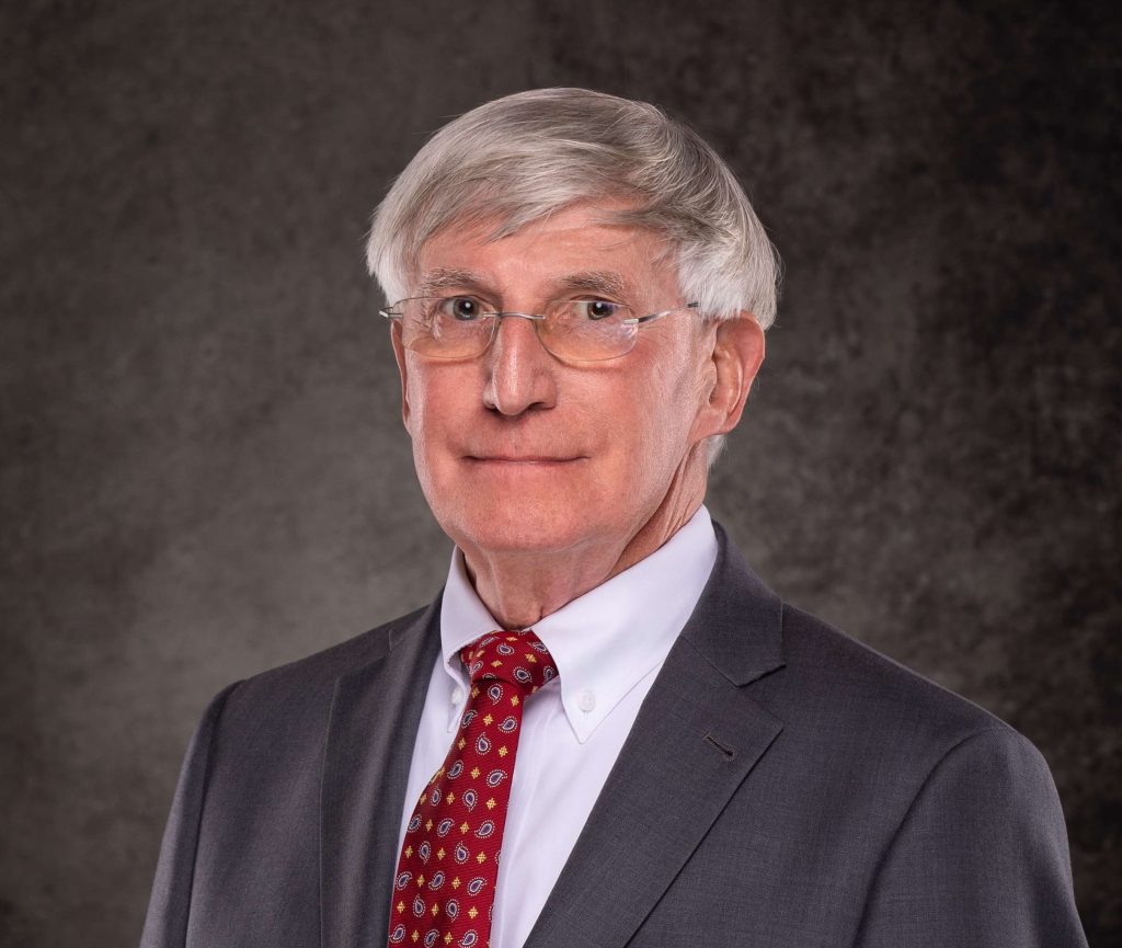 A professional headshot of a man in a suit and tie.