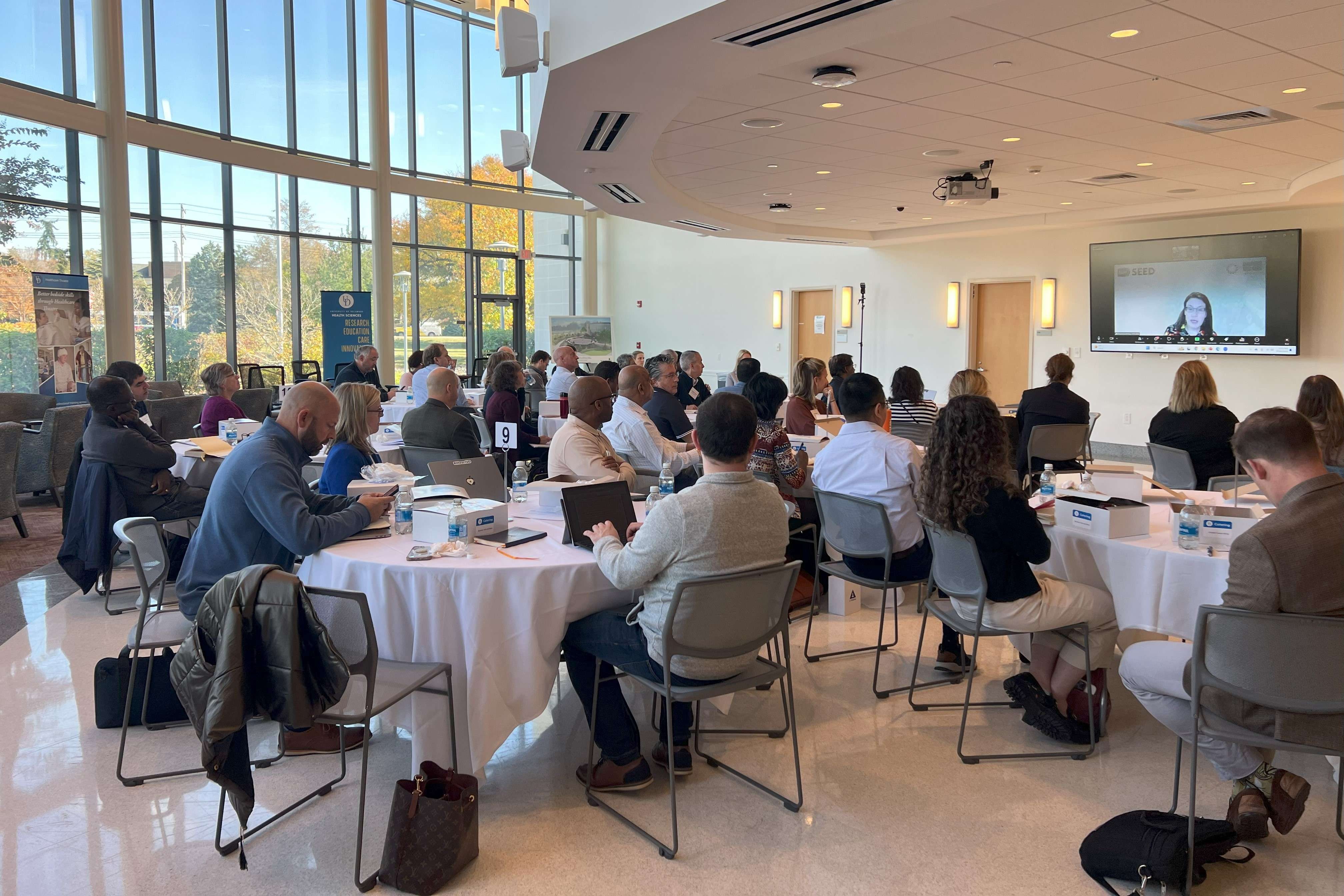 A group of people sitting at a roundtable listening to a presentation.