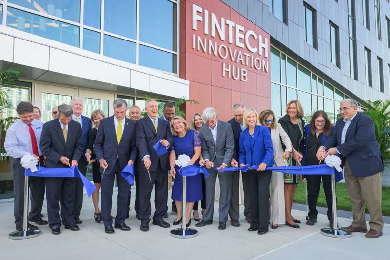 The president of University of Delaware with a group of people cutting the ribbon at Fintech Innovation Hub