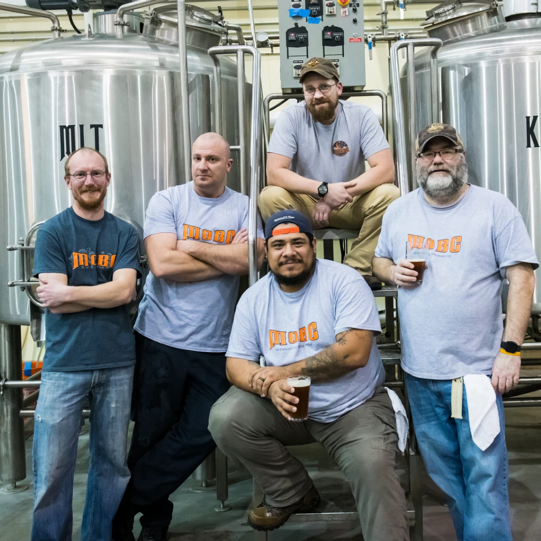 Five men standing in front of brewing barrels