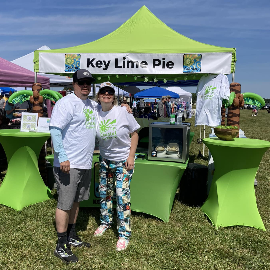 Two people in white shirts standing in front of a green tent.