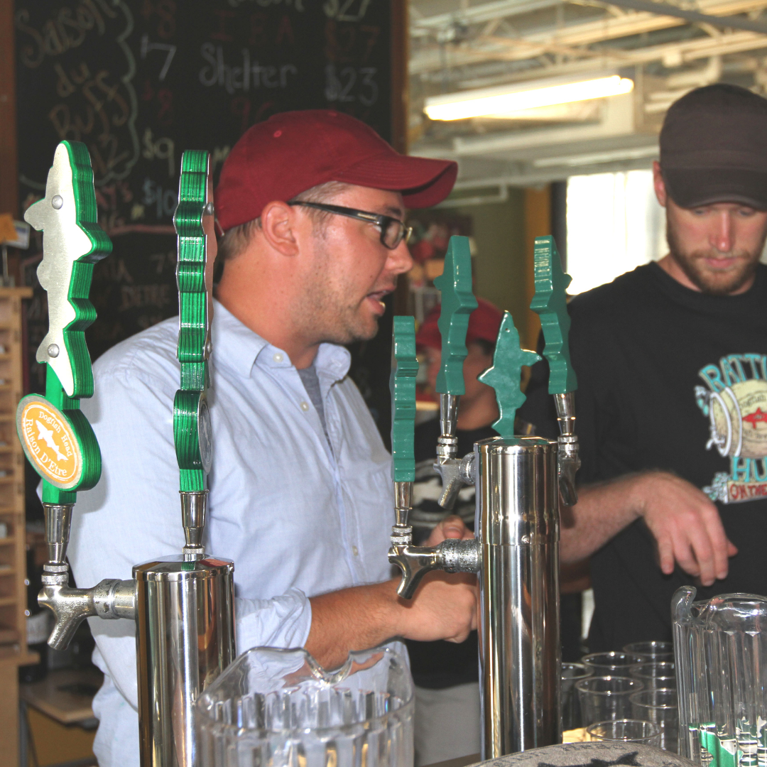 Two men standing at a bar with brewing tools.