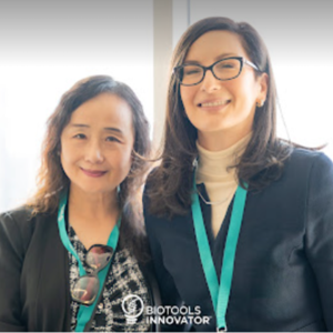 A headshot of two ladies in professional attire with green name tags.
