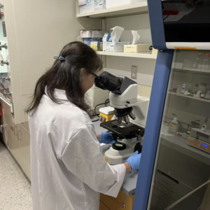 a lady wearing a lab coat and working with lab equipment.
