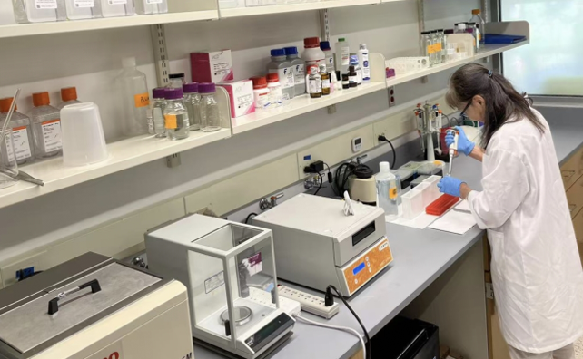 A woman wearing a lab coat and working with lab equipment.