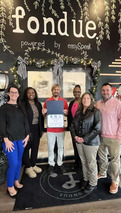 A group of people standing in a restaurant displaying a certificate.